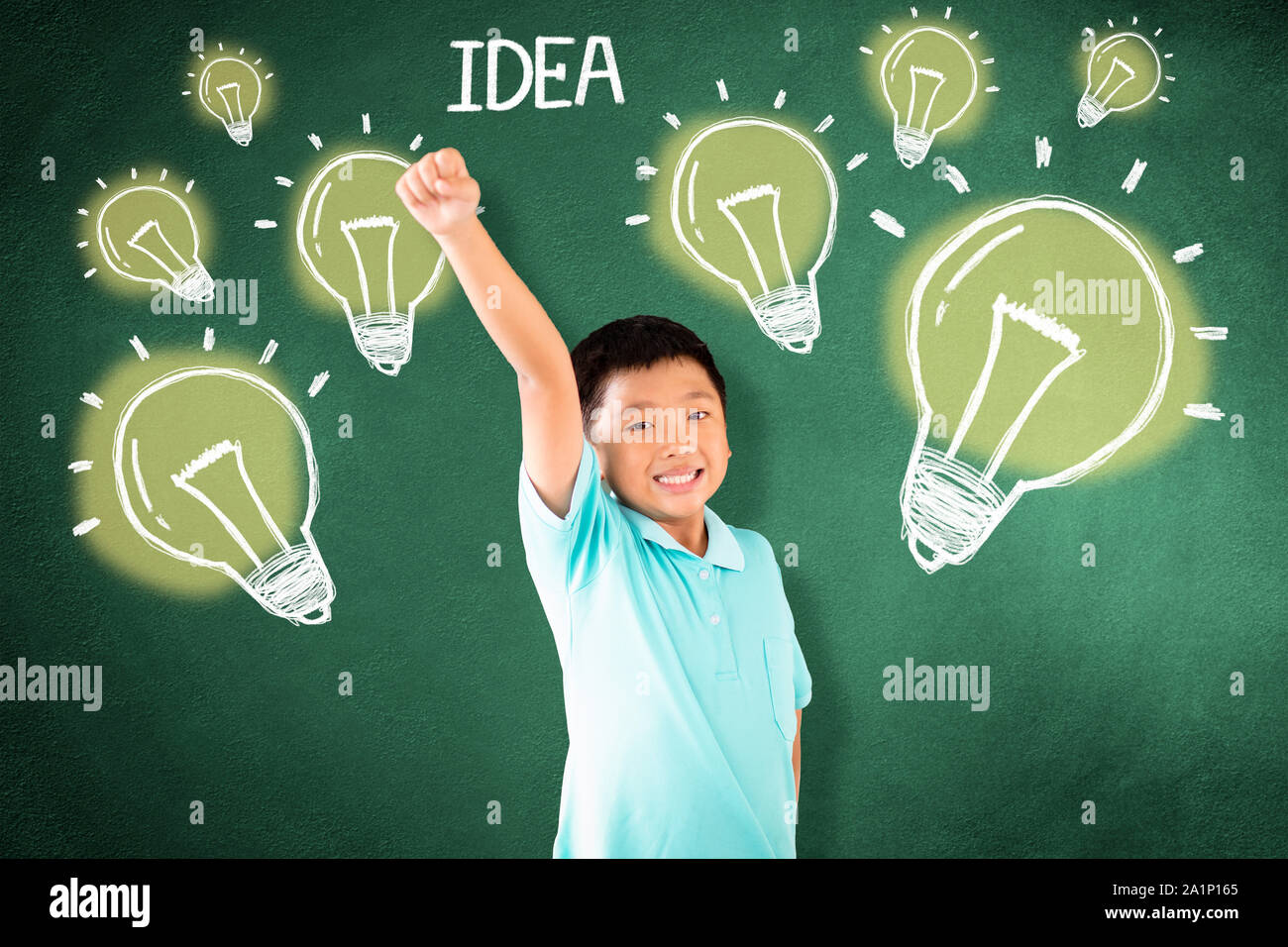 kid standing against chalkboard with idea bulb concept Stock Photo