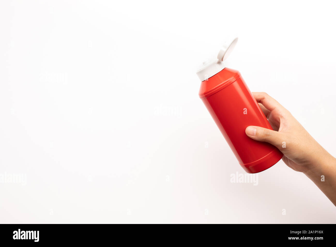Youngwoman hand squeezing bottle of tomato sauce ketchup on white