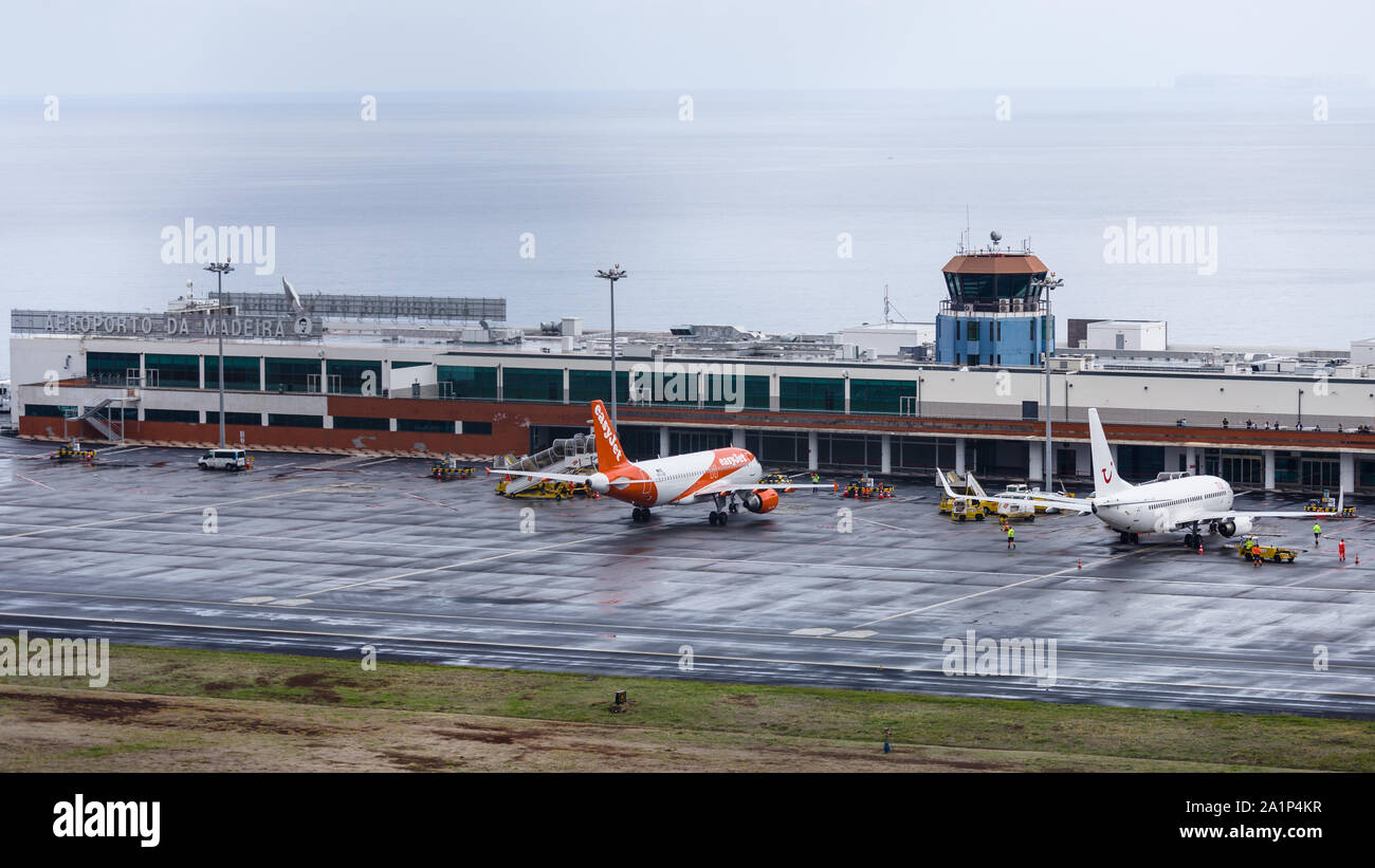 FUNCHAL, PORTUGAL - SEPTEMBER 2019: An Easyjet and TUI airplanes docket at Cristiano Ronaldo International Airport at Madeira in a rainy day. Stock Photo