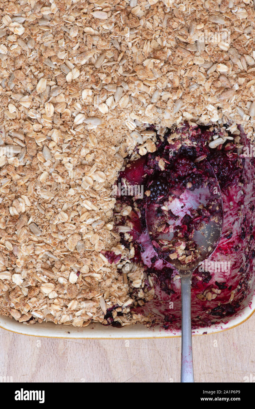 Homemade Blackberry and apple crumble with a tablespoon. Organic Oat and seed crumble with foraged blackberries and apples Stock Photo