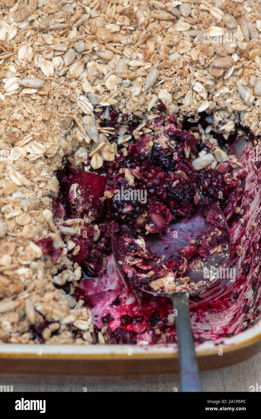 Homemade Blackberry and apple crumble with a tablespoon. Organic Oat and seed crumble with foraged blackberries and apples Stock Photo