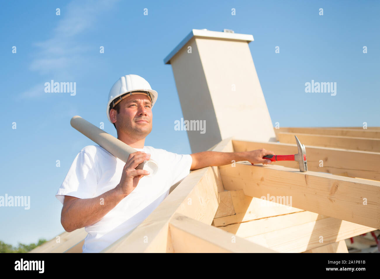 Young architect with blueprint on the top of a house that is currently under construction Stock Photo