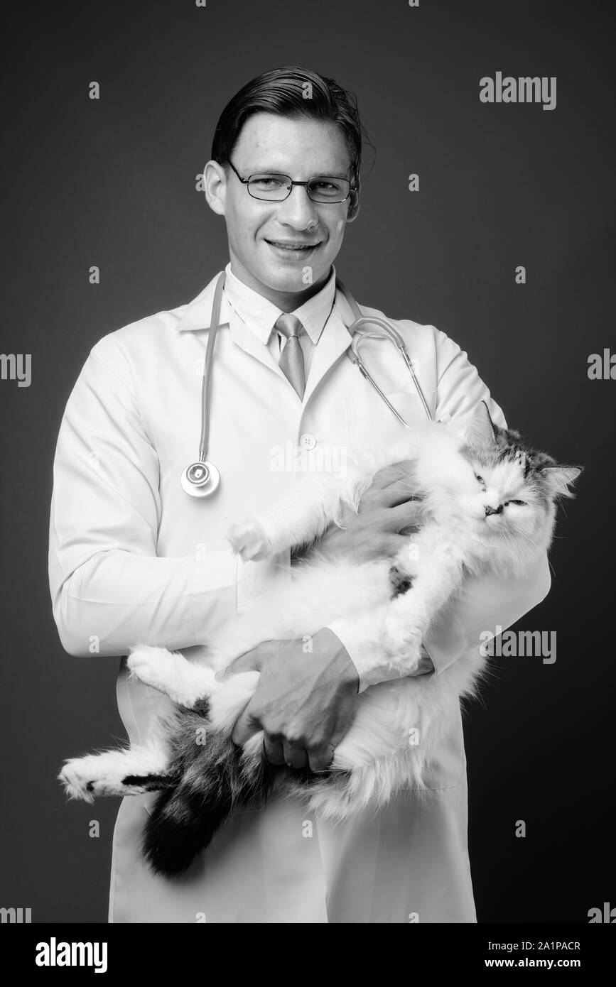 Studio shot of man doctor holding Persian cat in black and white Stock Photo