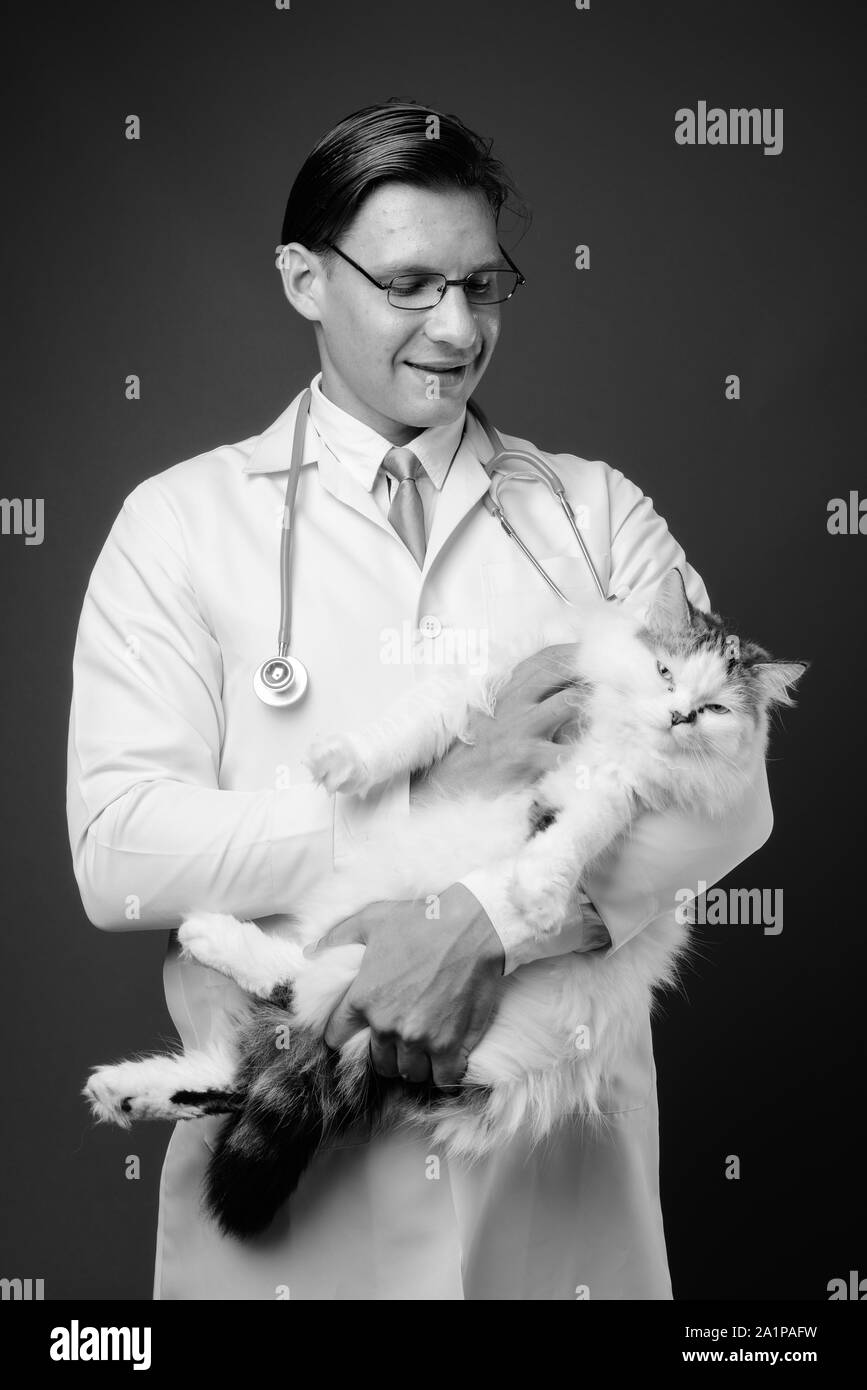 Studio shot of man doctor holding Persian cat in black and white Stock Photo