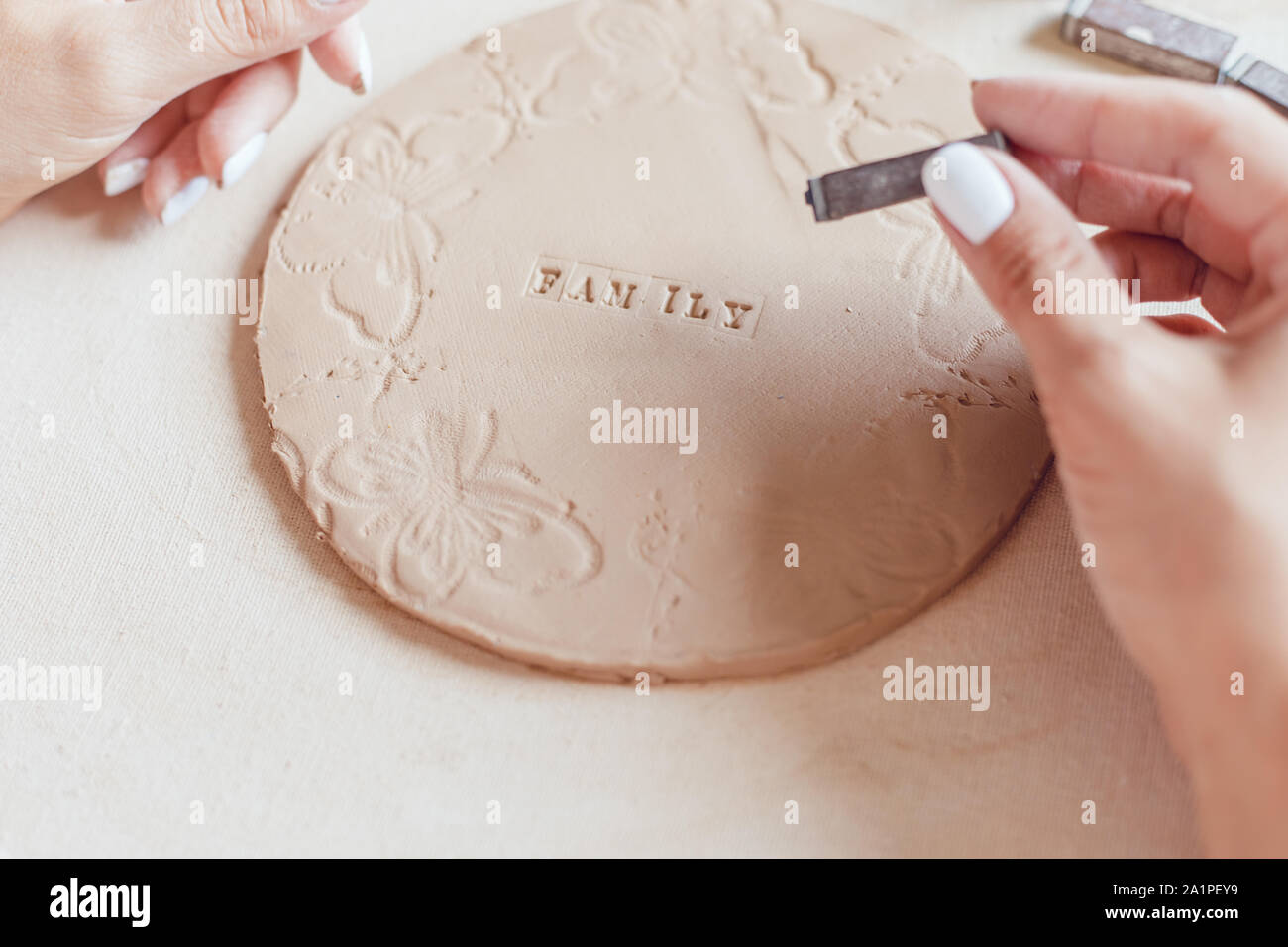 Hands make a round clay product with the words 'Family'. Stock Photo
