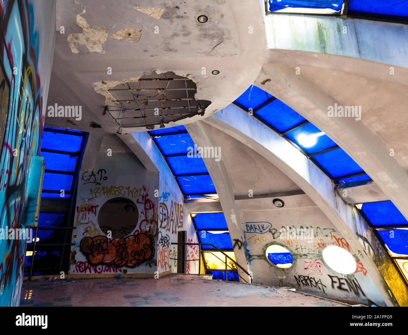 Abandoned interior of concrete building with dome and blue glass windows from below at ancient Hue water park, Vietnam Stock Photo