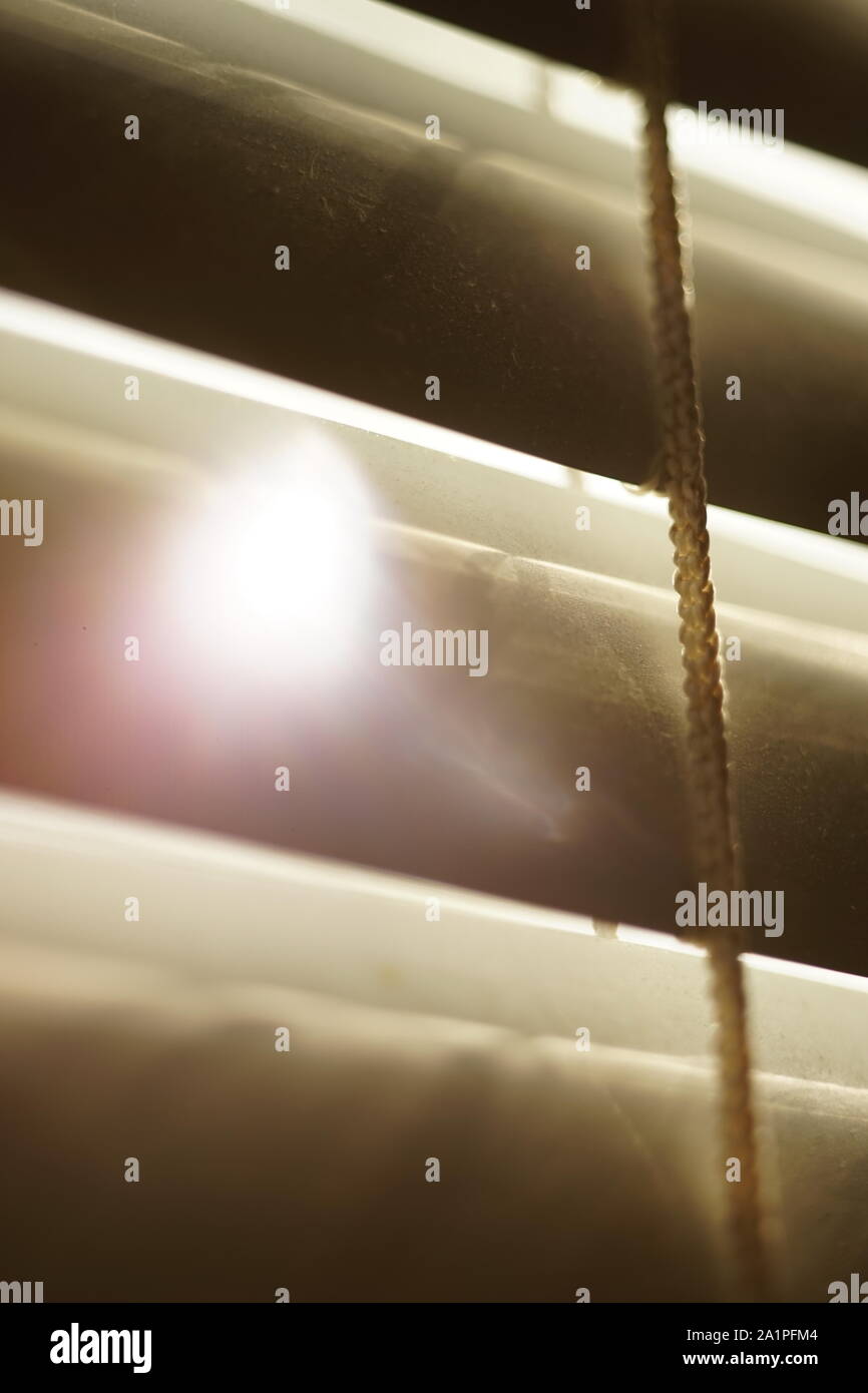 closed horizontal blinds through which the sun shines Stock Photo
