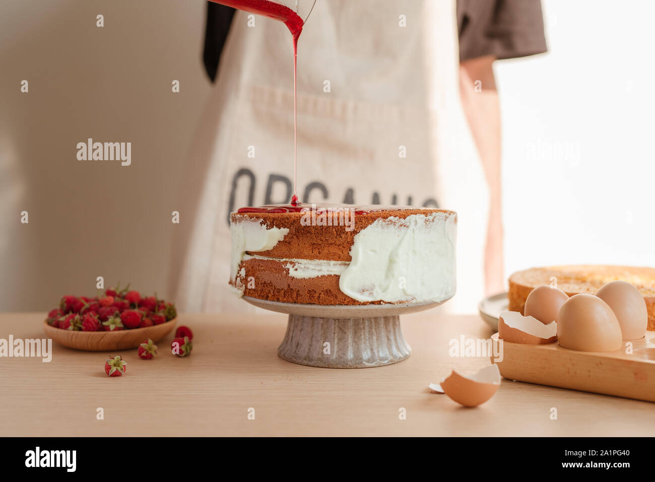 fresh sponge cake with raspberry syrup being poured over the top. Making red velvet or sponge cake process Stock Photo