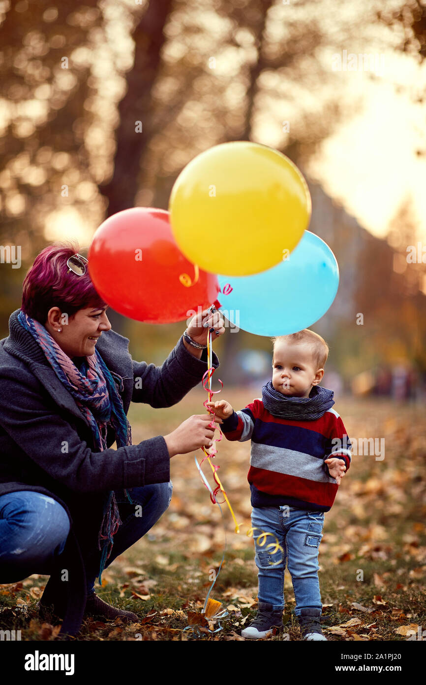 Little boy. Happy childhood. little child boy with a bunch of balloons in their hands in yellow autumn park. Family. Stock Photo