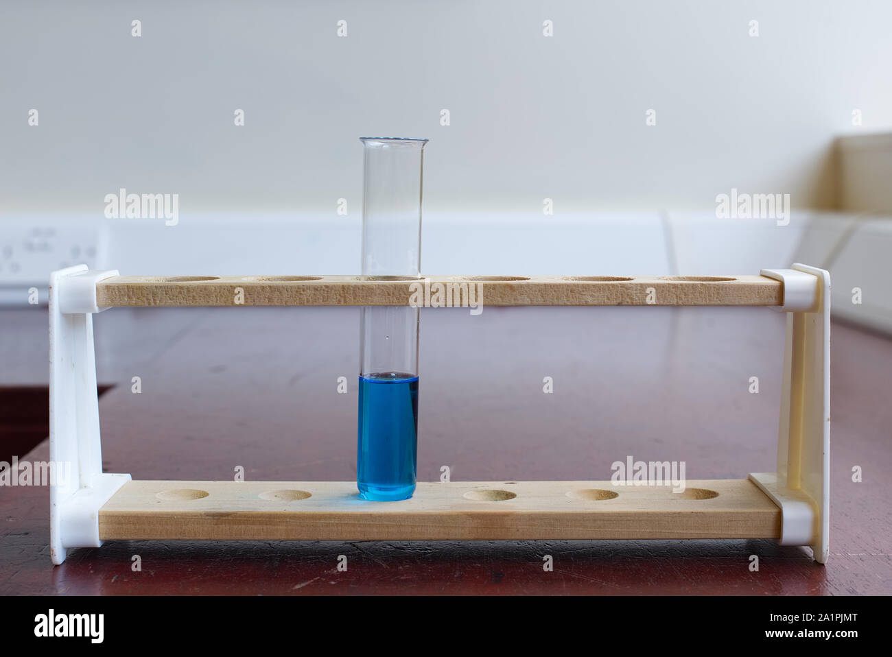 Wooden test tube rack with boiling tube of copper sulfate solution in an old school science laboratory. Science education lab concept Stock Photo