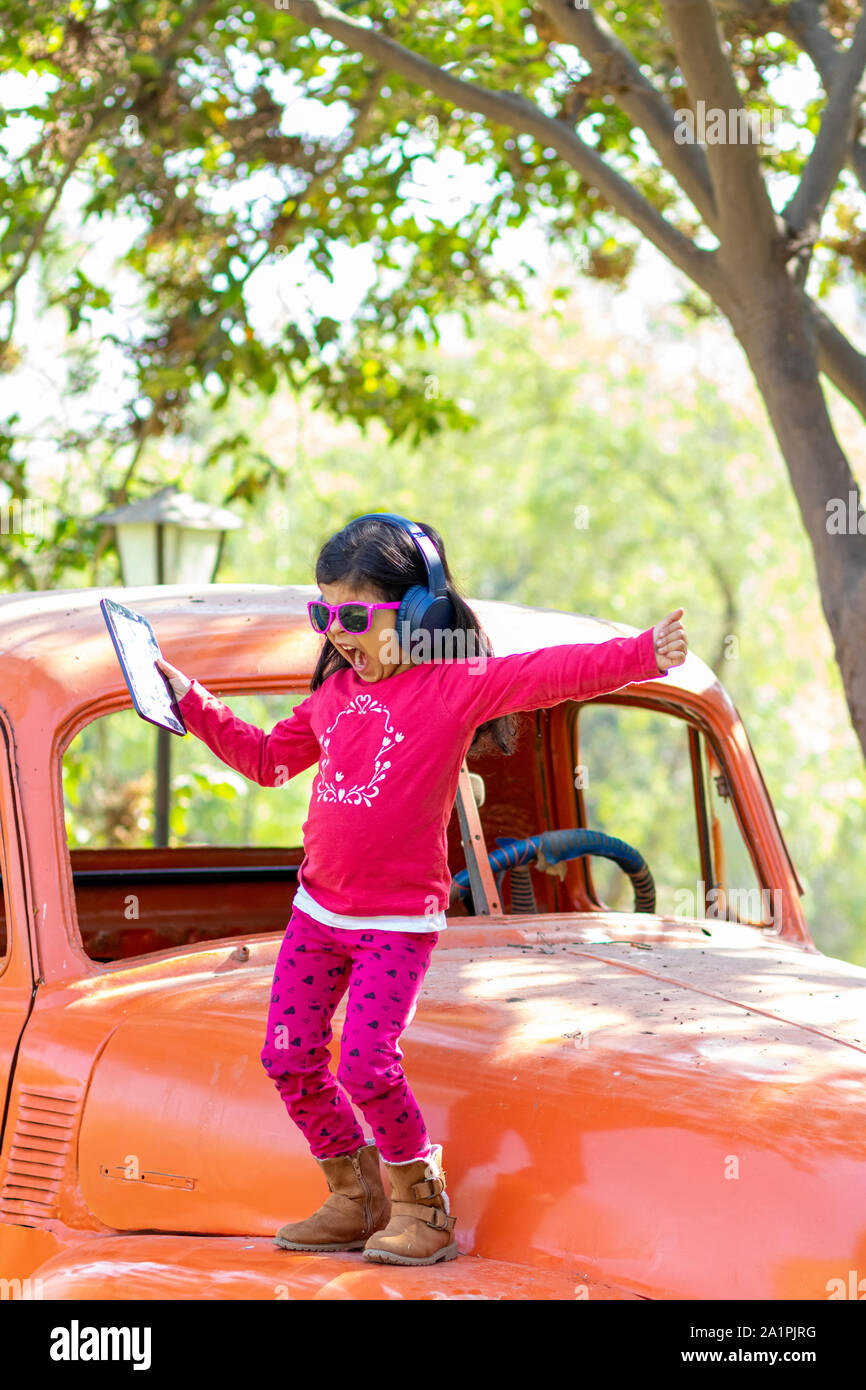 Little girl listening to music on the tablet with her headphones in the truck car Stock Photo