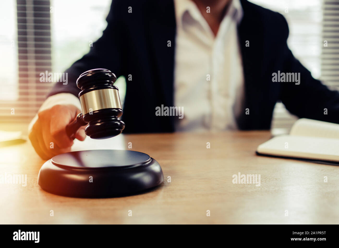 justice lawyer in black suit knocking wooden judge gavel with documents on workplace desk in courtroom office, consultant lawyer service Stock Photo