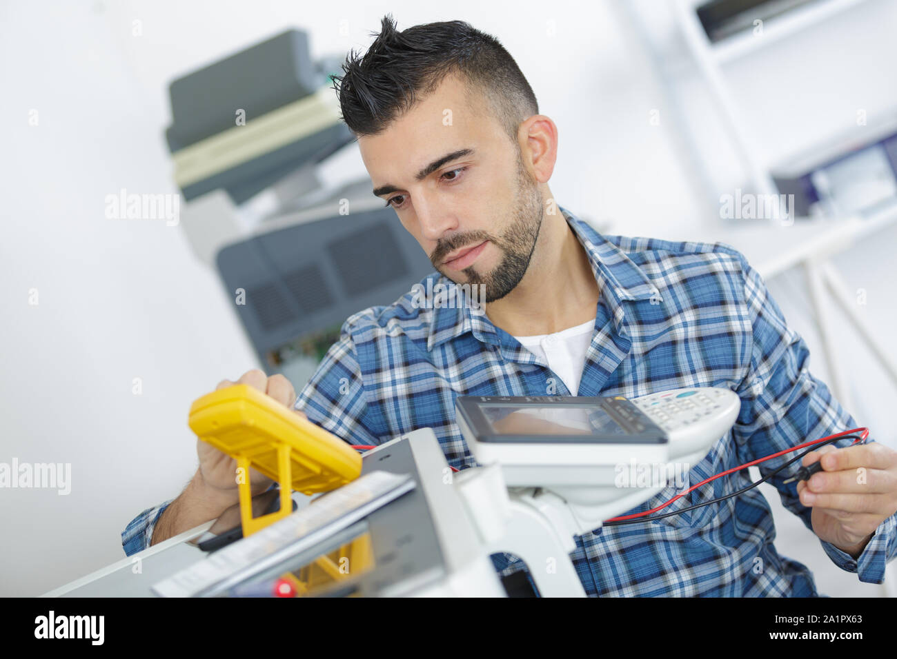 technician testing phoocopier using multimeter Stock Photo