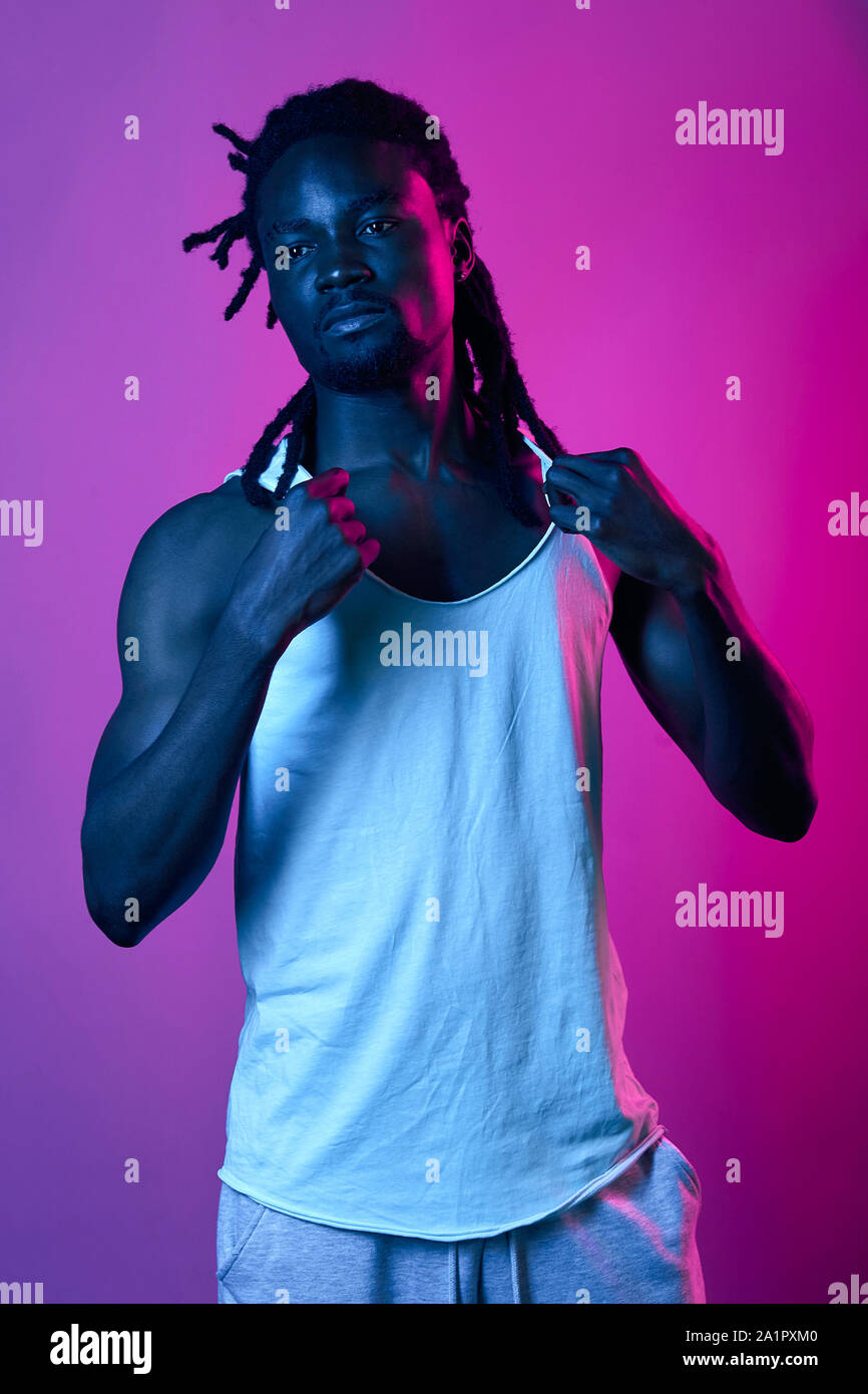 attractive afro man advertising a white singlet, close up photo. isolated violet background, studio shot, Stock Photo