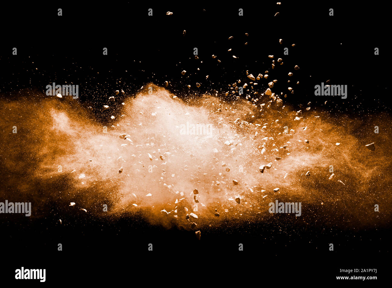 Split debris of stone exploding with orange powder against black background. Stock Photo