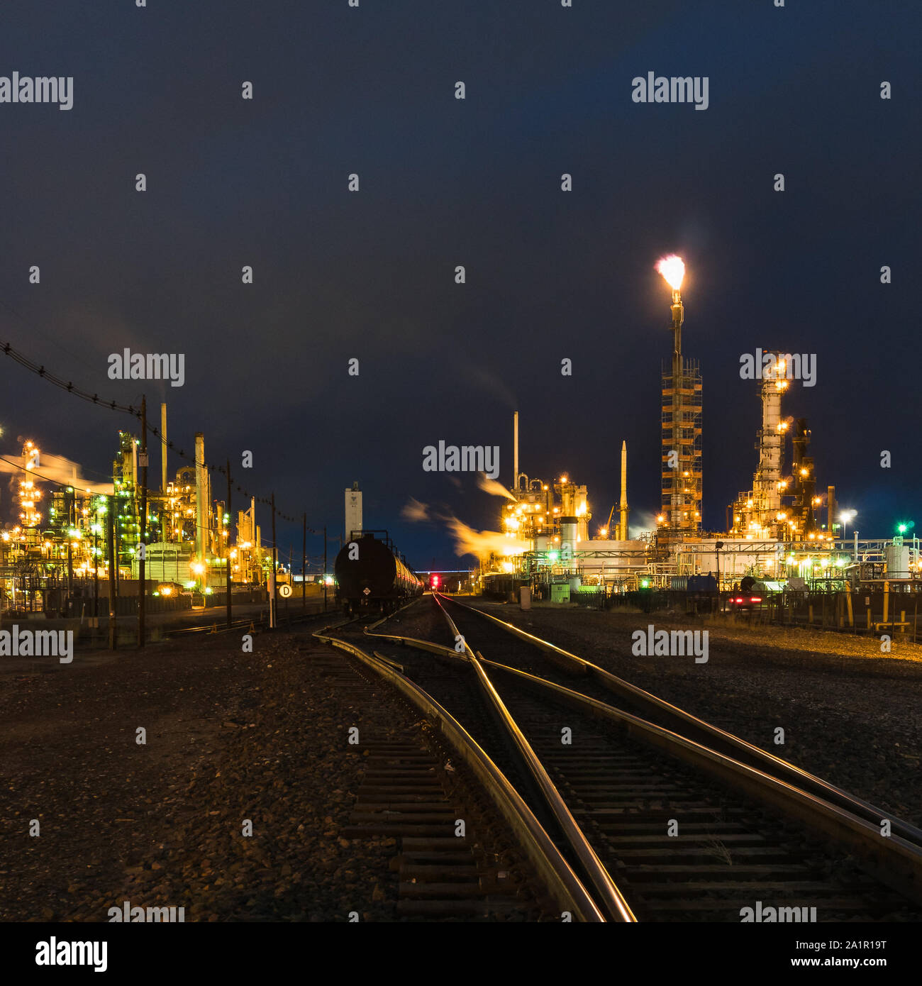 Train Tracks leading to industrial stacks Stock Photo