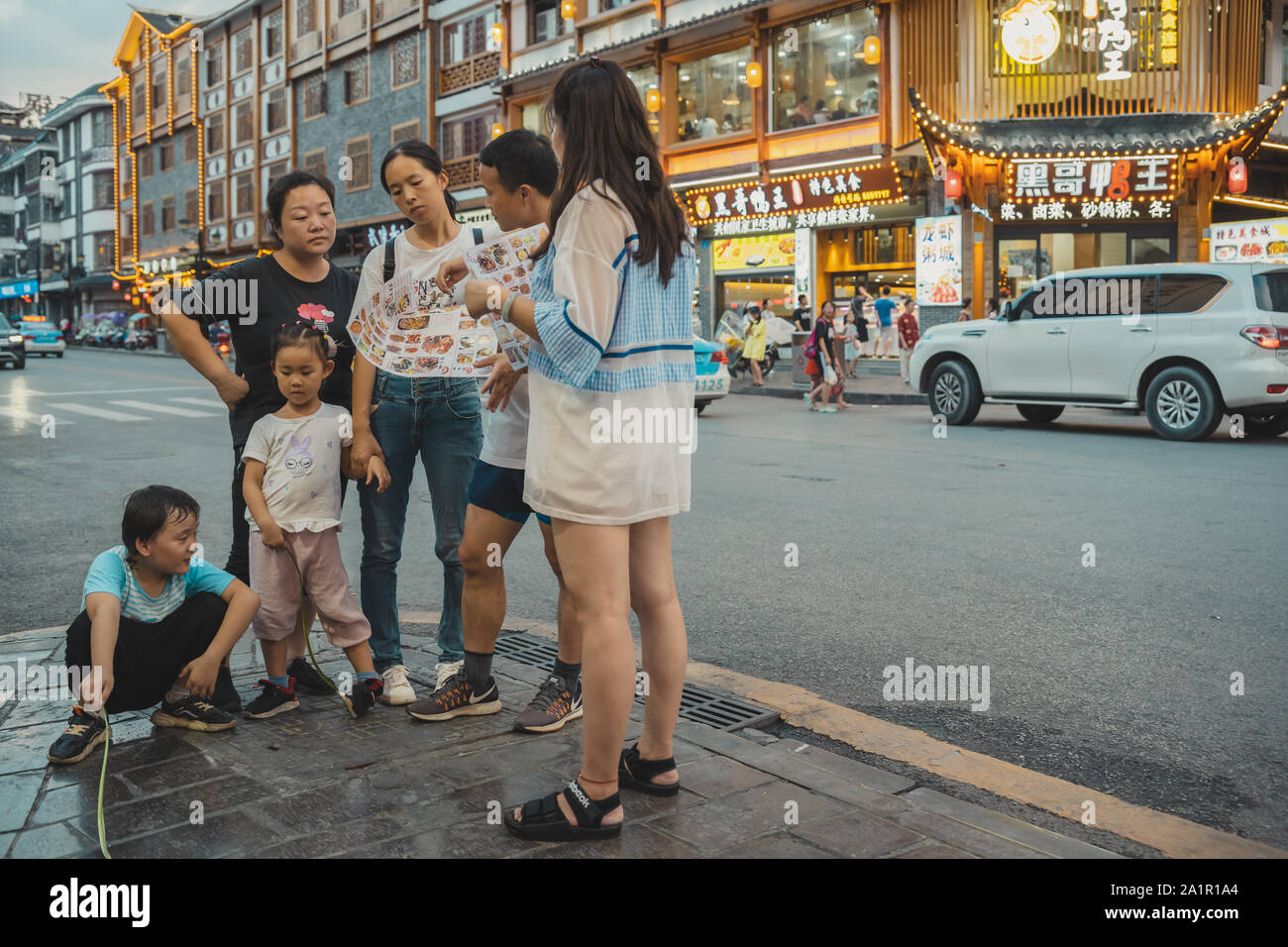 Wulingyuan, China - August 2019 : Chinese family standing outside restaurant and deliberating over menu Stock Photo