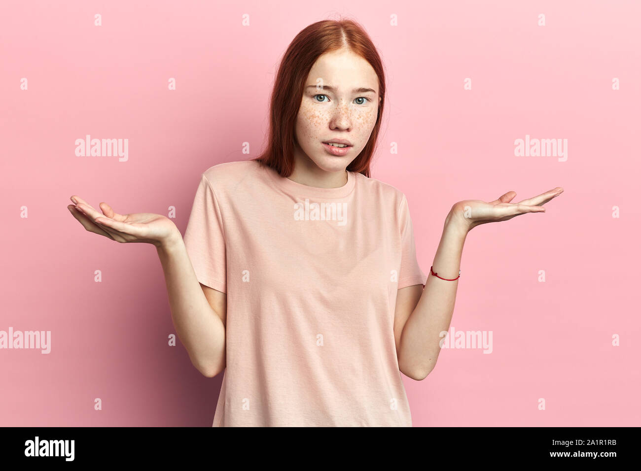 serious woman shrugs her shoulders, student doesn't know how to pass exams. close up portrait, isolated pink background, studio shot. Stock Photo