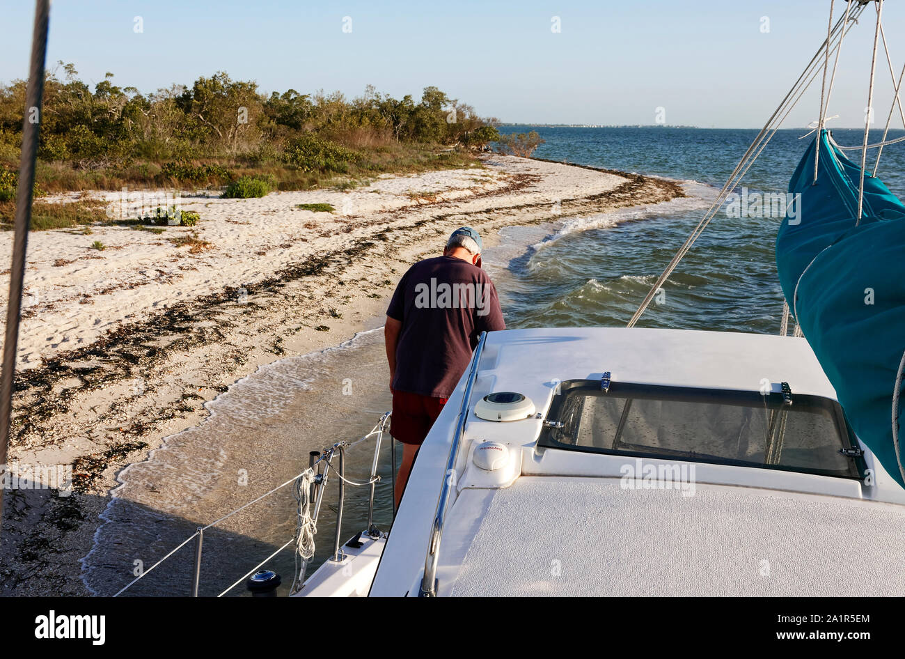 catamaran sailboat grounded, sand beach, man, captain, stuck, mistake, Charlotte Harbor, Florida, FL; horizontal; MR Stock Photo