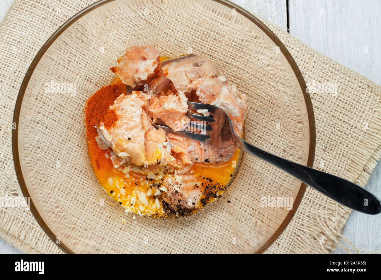 Preparation of fish croquettes from canned salmon, egg yolks, onion, coconut butter and spices. All ingredients in glass bowl Stock Photo