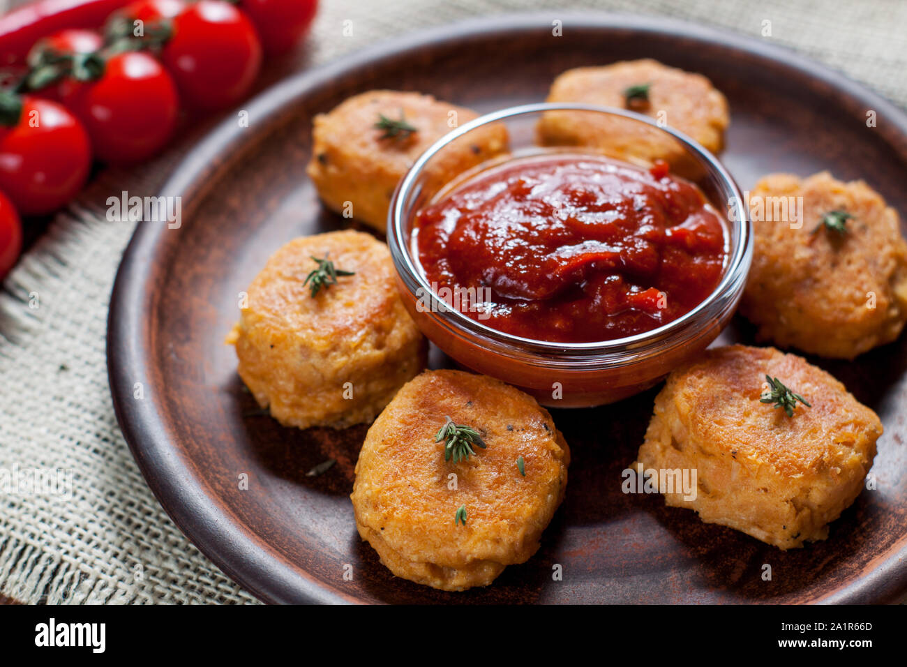 Homemade fried fish croquettes from canned salmon, egg yolks, onion, coconut butter and spices, served with tomato sauce and cherry tomatoes Stock Photo