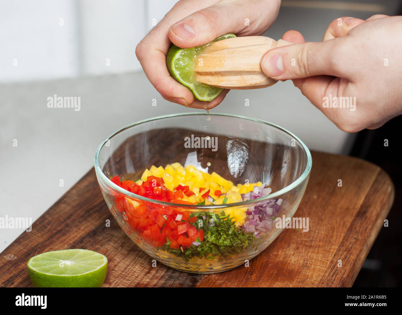 Man preparing mango salsa, squeezing lime juice Stock Photo