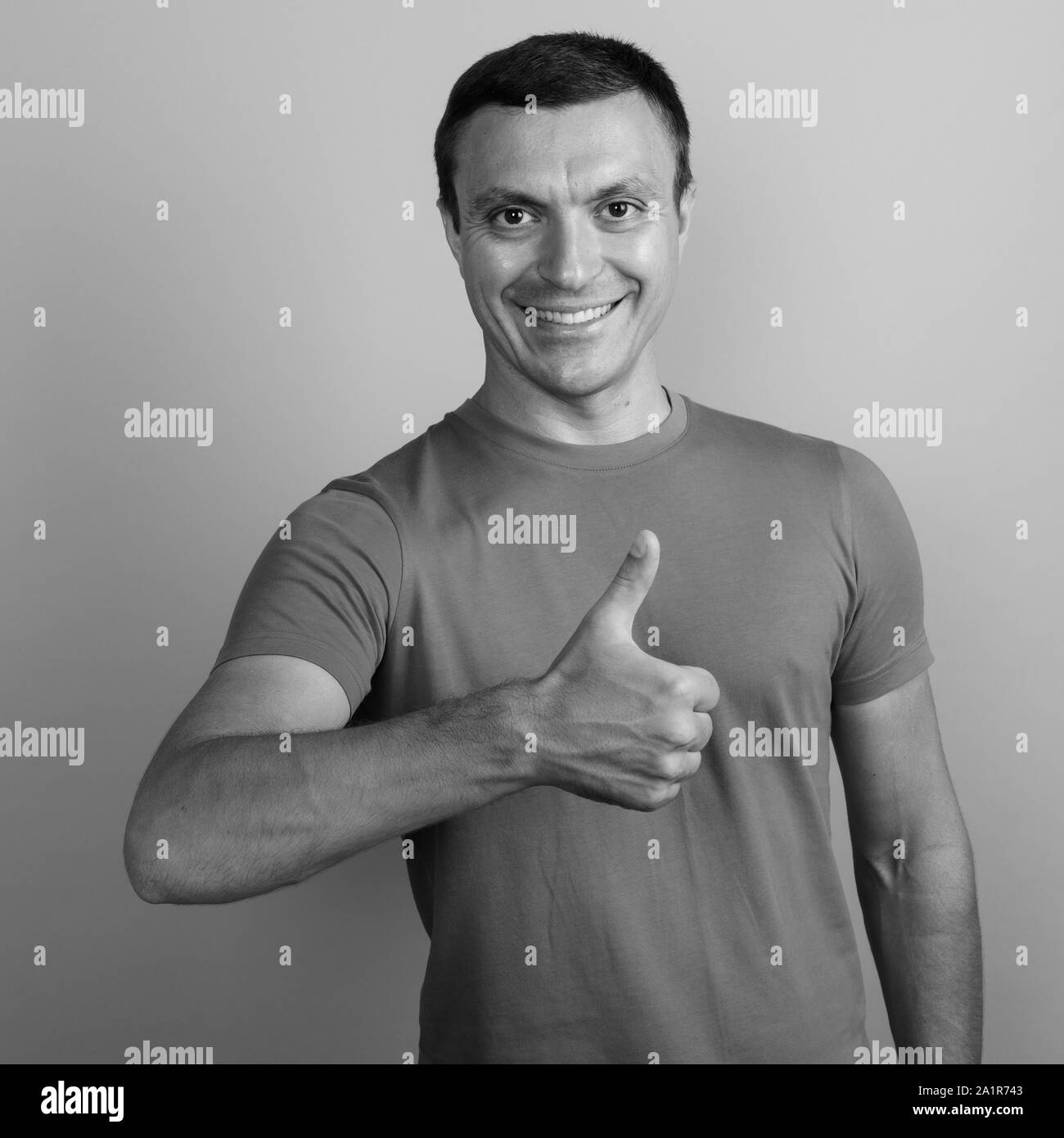 Man wearing t-shirt against gray background shot in black and white Stock Photo