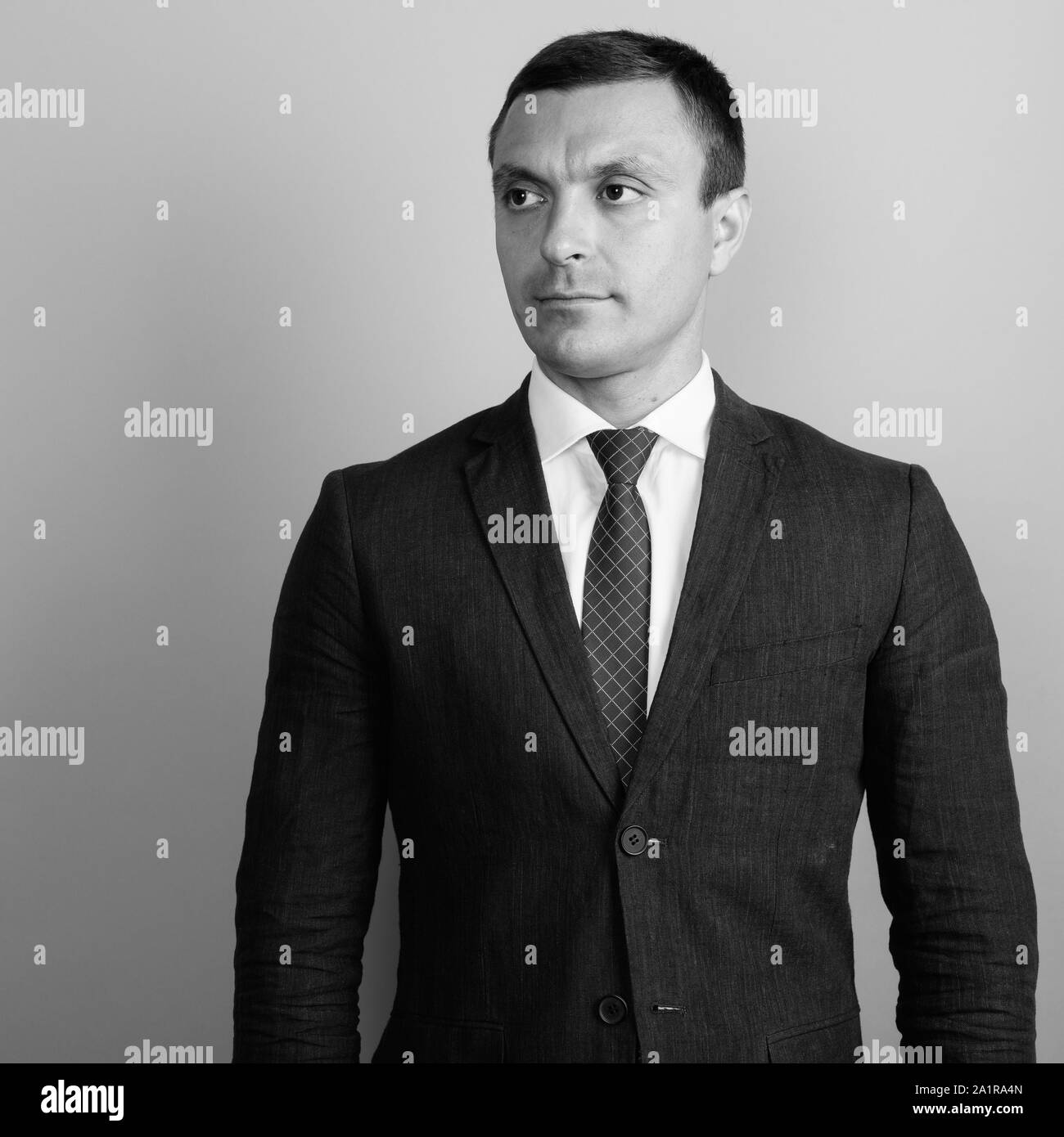 Businessman wearing suit against gray background shot in black and ...