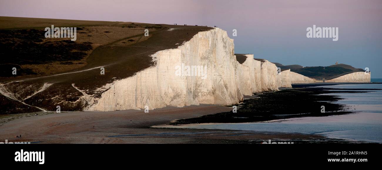 A dramatic panoramic view of the Seven Sisters at sunset. The Seven Sisters are a series of white chalk cliffs by the English Channel. Stock Photo