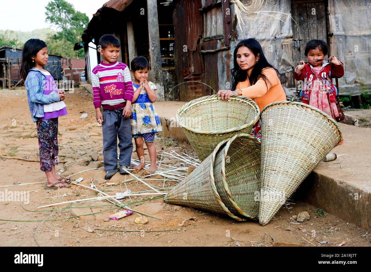woman weaving bamboo baskets surroundet by her children in the village