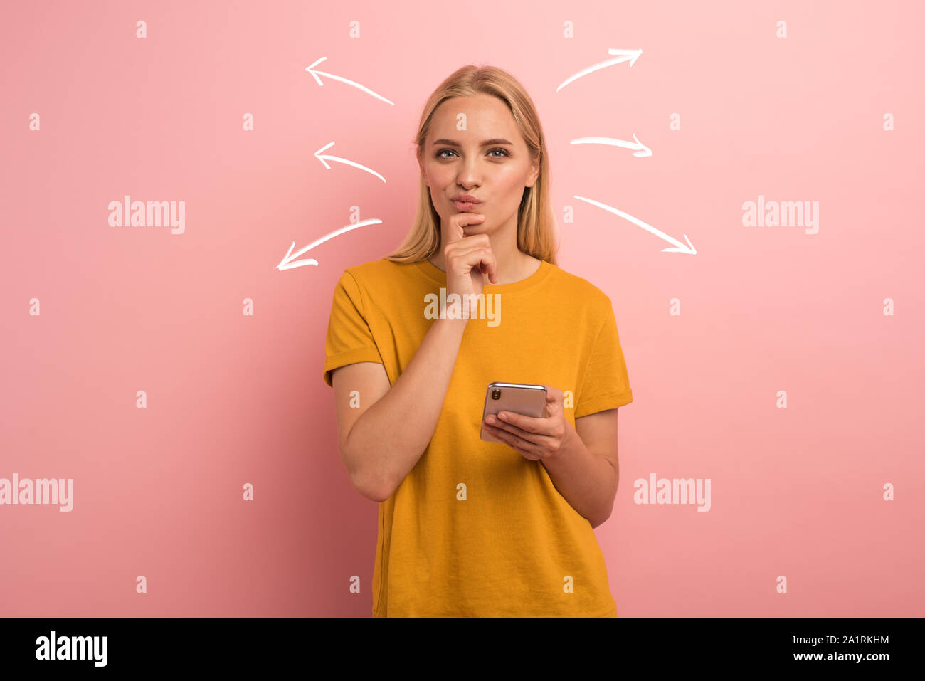 Blonde girl thinks about the right option. Confused and pensive expression. Pink background Stock Photo