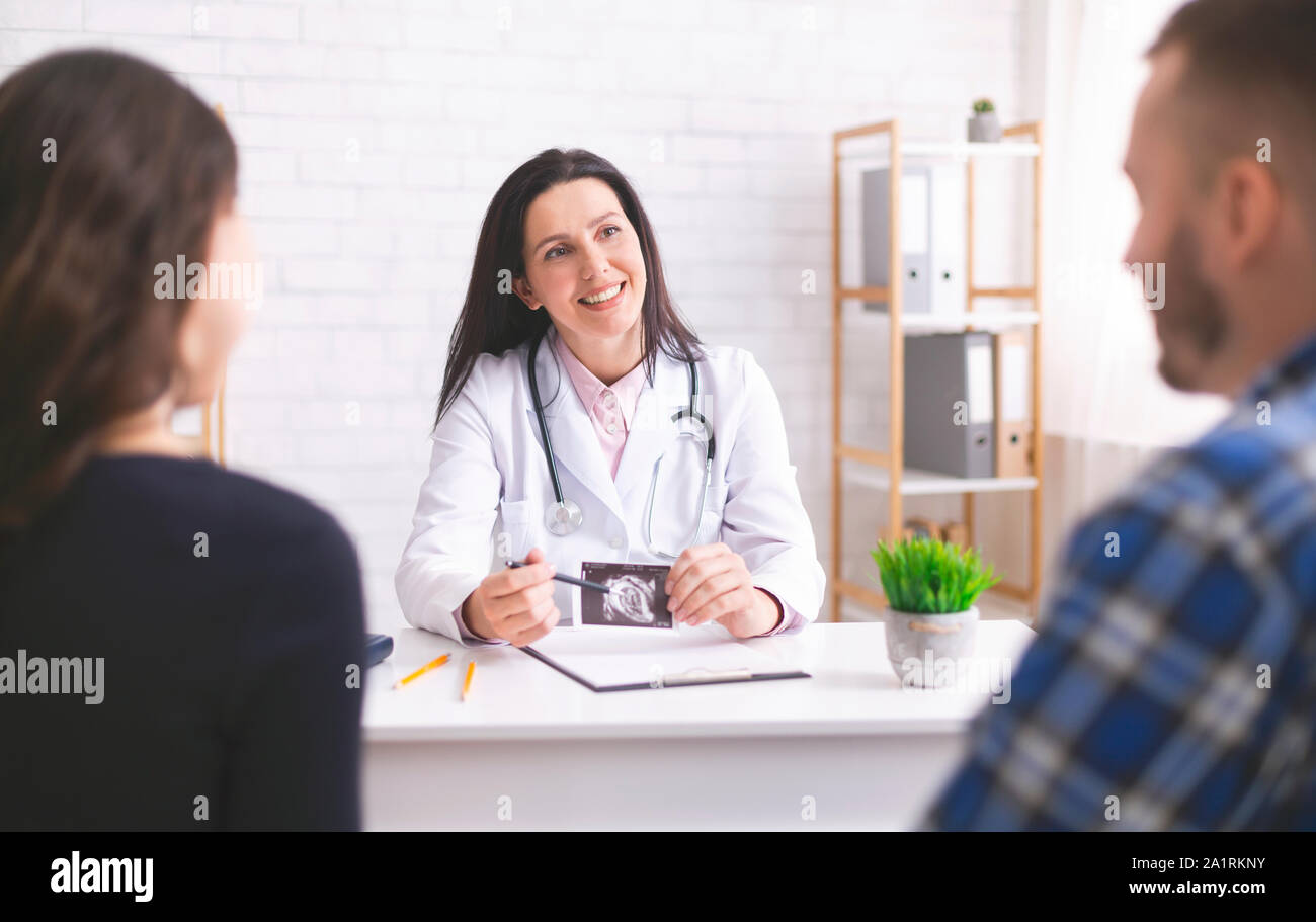 Friendly doctor explaining pregnancy diagnosis to young couple Stock ...