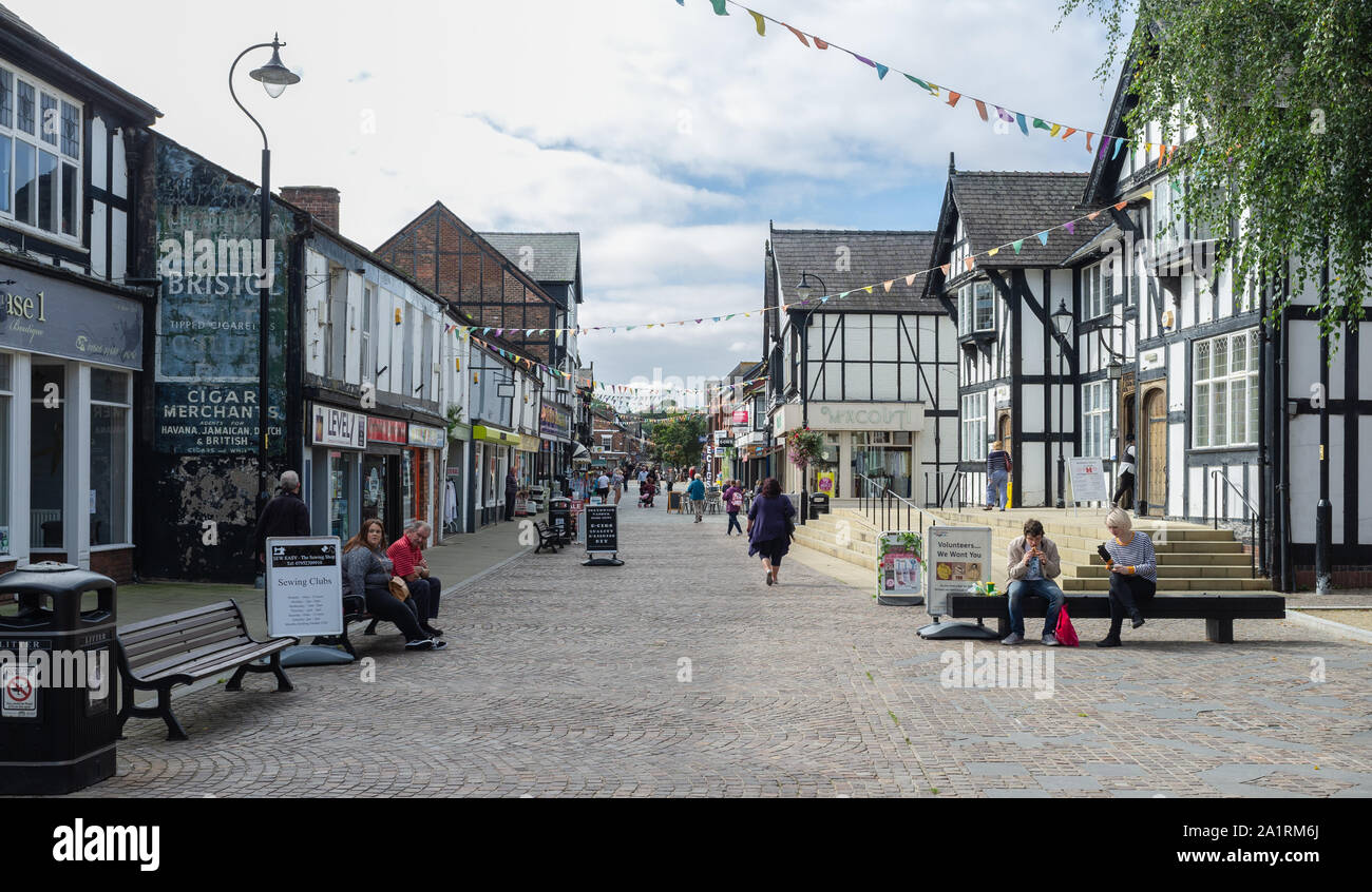 Northwich town centre, Cheshire, on an overcast, quiet mid-week day. Bunting hangs above the cobbled street, whilst shoppers sit or stroll through. Stock Photo