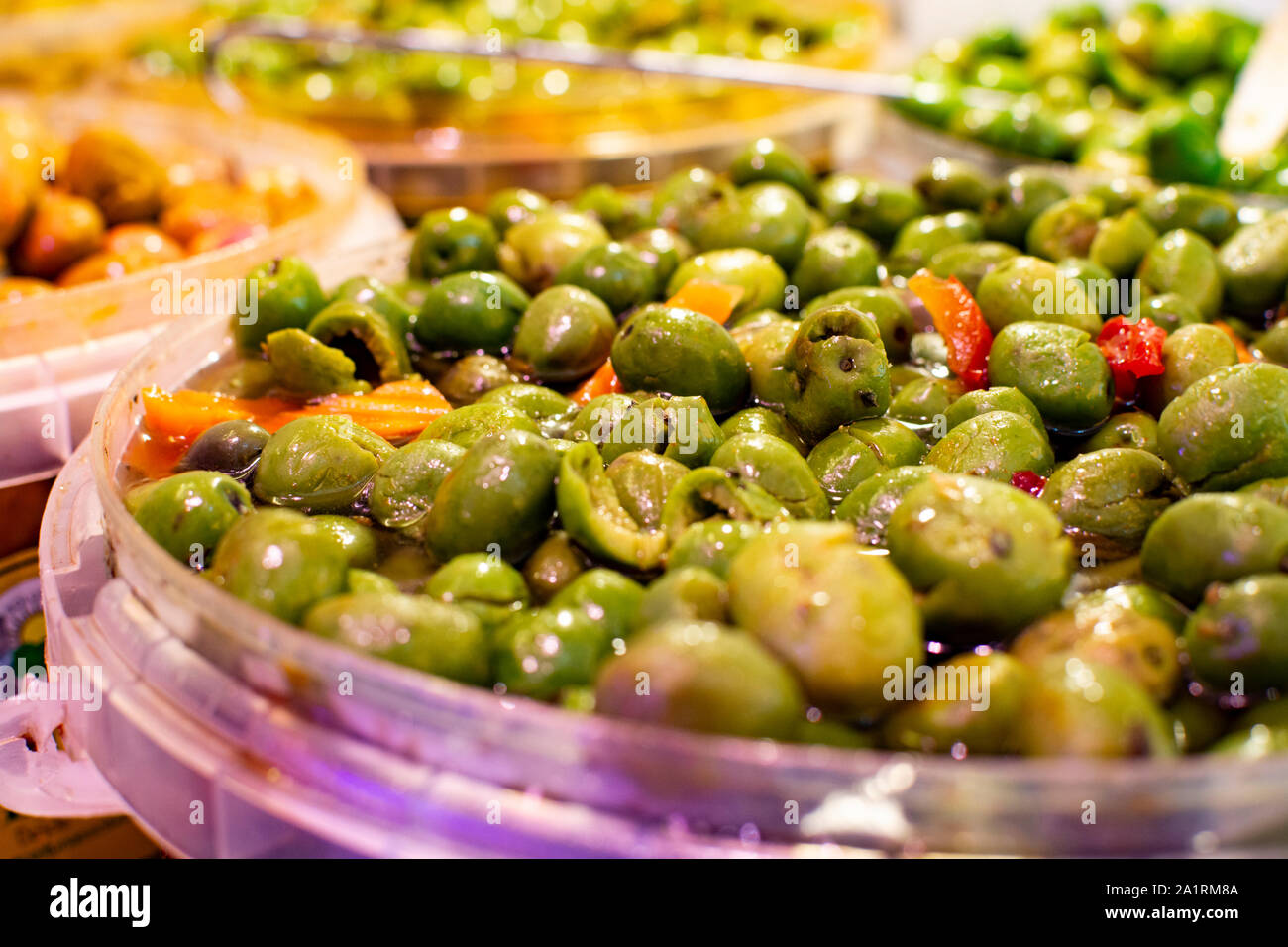 Homemade pickled green olives with garlic and spices in bucket on spanish market Stock Photo
