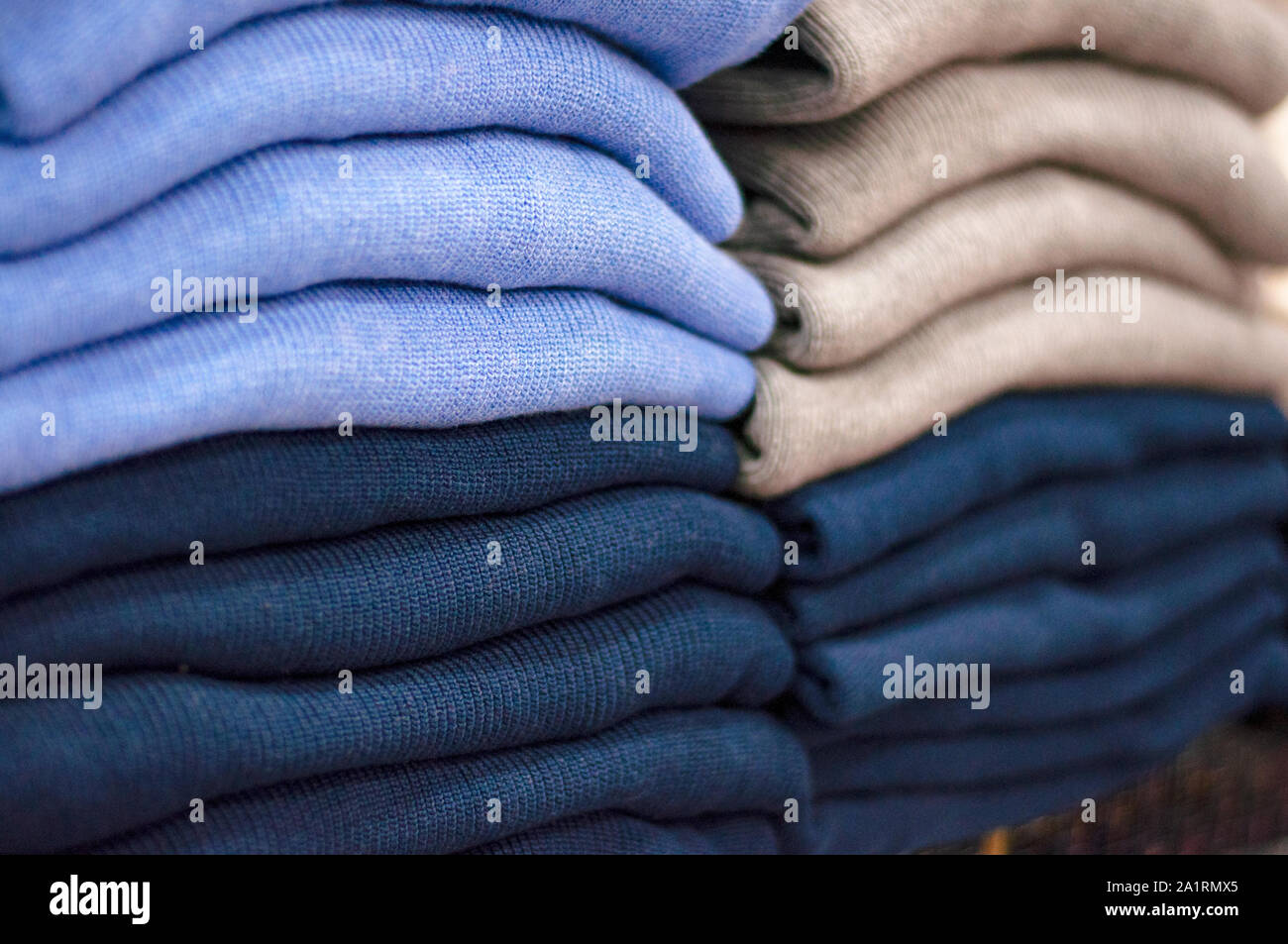 Warm clothing neatly folded on a store shelf. Sweatshirts, sweaters, jumpers, cardigans, hoodies, bobmers with piles on the shelf. Clothes storage. Si Stock Photo