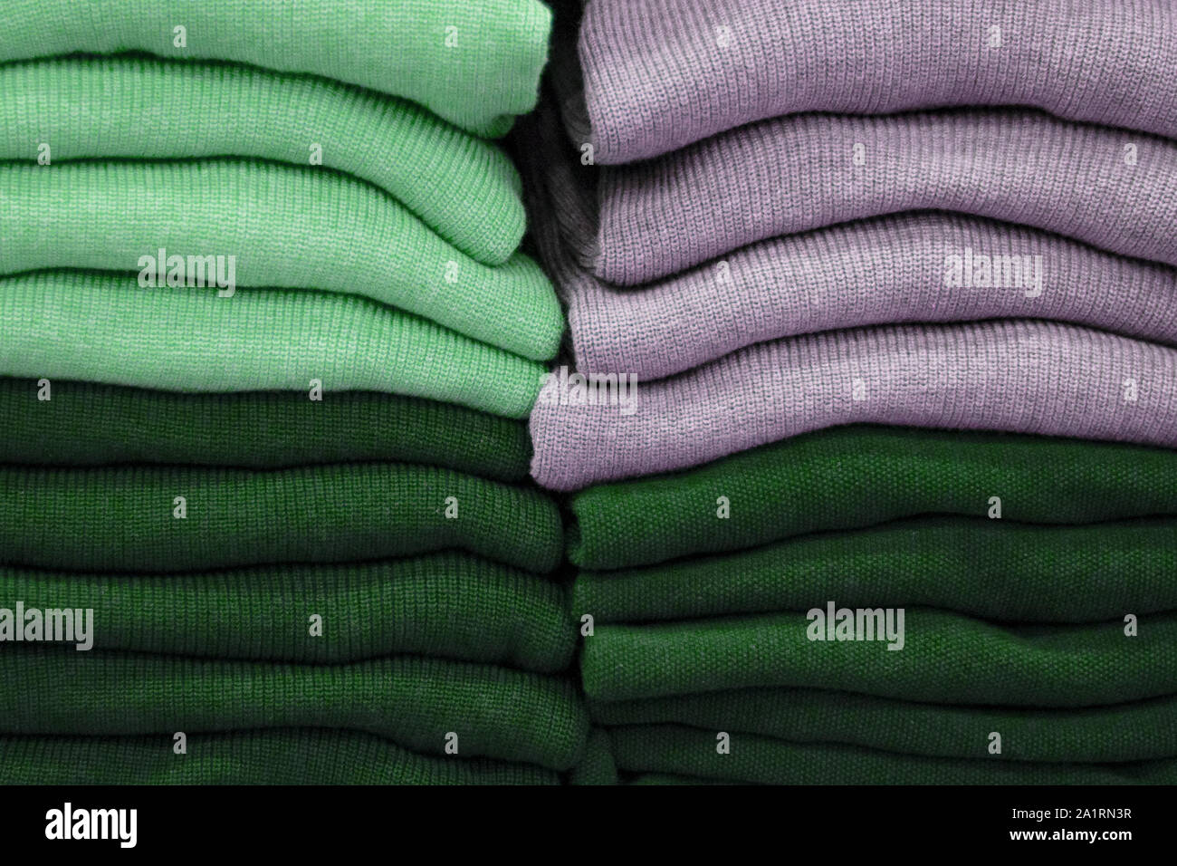 Warm clothing neatly folded on a store shelf. Sweatshirts, sweaters
