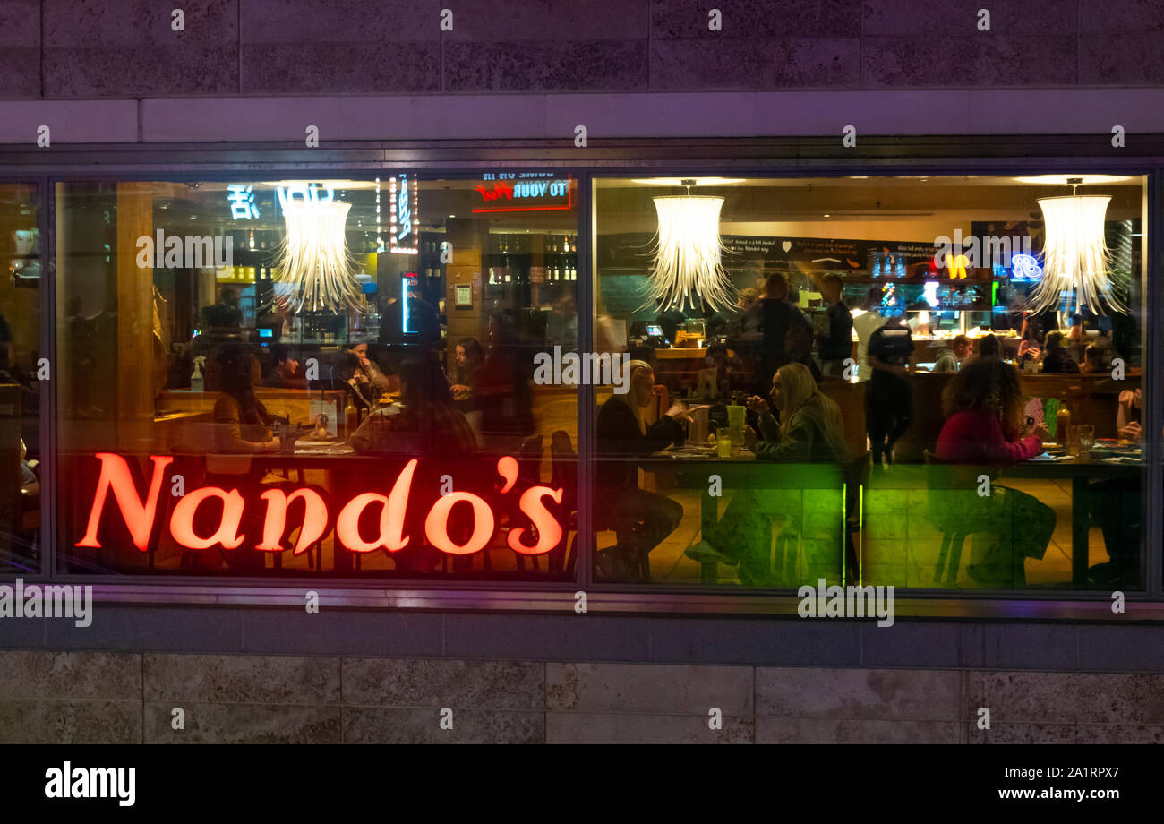 Dining at Nando's South African restaurant at night in Liverpool One shopping centre, England Stock Photo