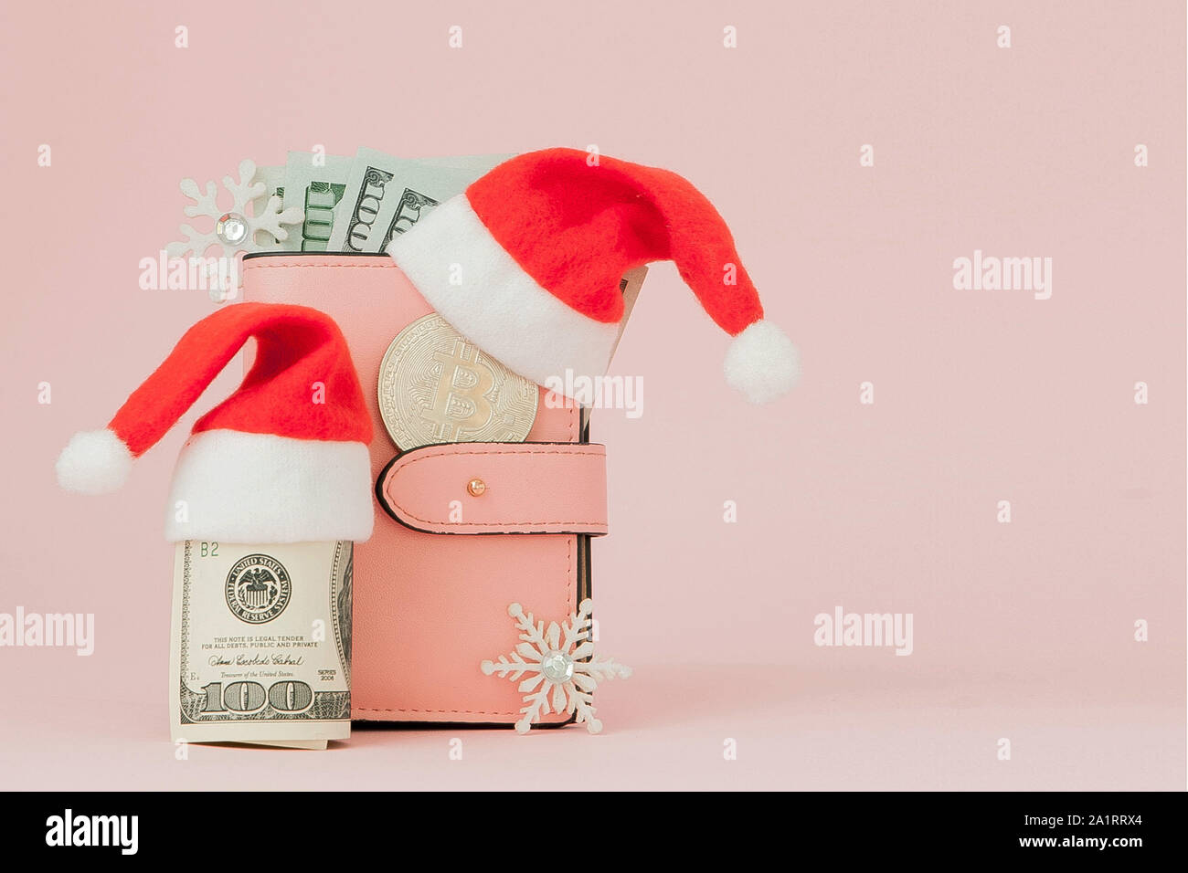 Christmas expenses. Pink leather purse with santa claus cap, gift, fir tree and dollars banknotes on pink background. Christmas shopping. Holiday Sale Stock Photo