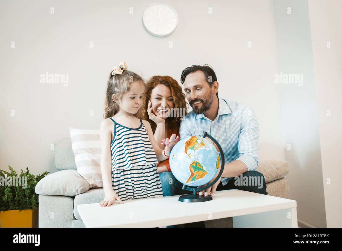 Going on adventure, mom, dad and daughter studying globe. Stock Photo