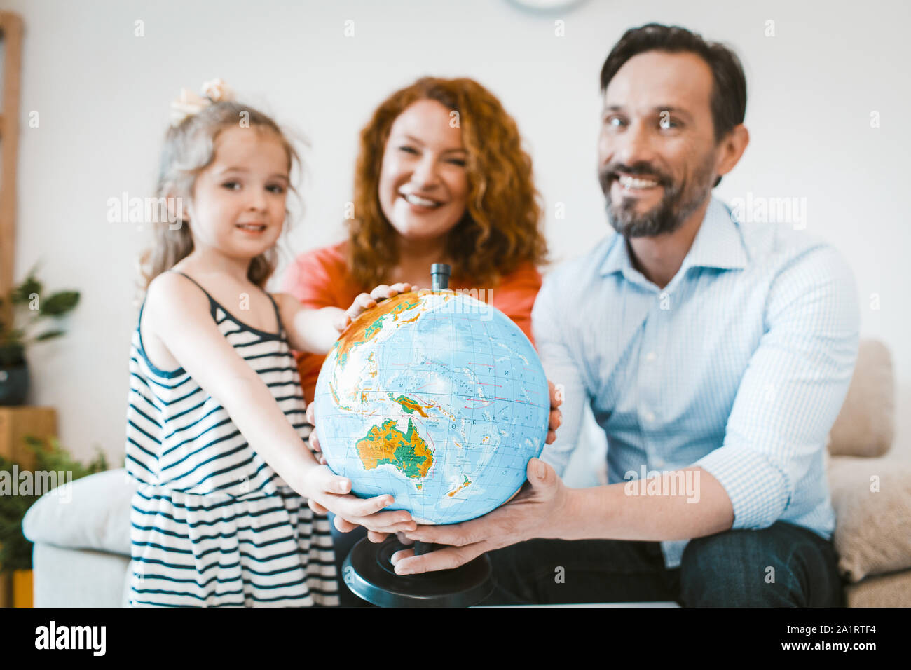 Mom, dad and little girl planning vacation, holding globe. Stock Photo