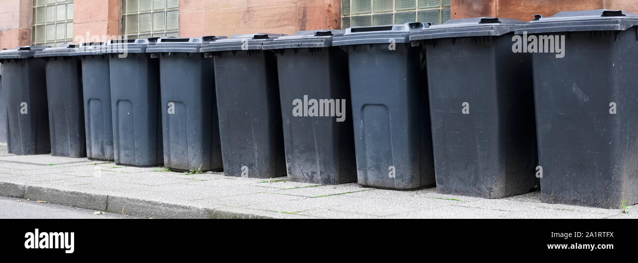 Black wheelie bins in a row on street with house numbers printed on