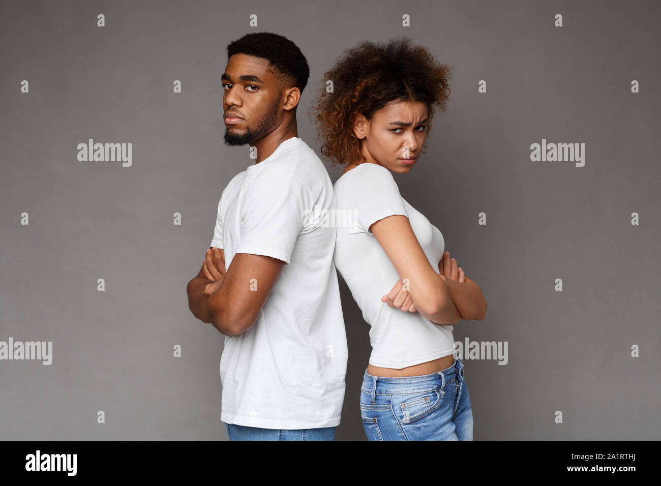 Offended african man and woman standing back to back with crossed hands Stock Photo