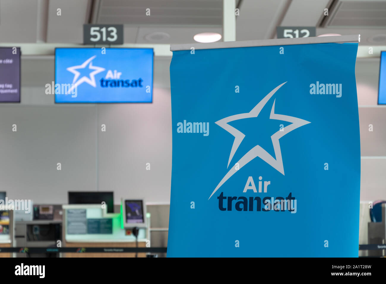 Air Transat logo on a poster in-front of a check-in desk at Toronto Pearson Intl. Airport. Stock Photo