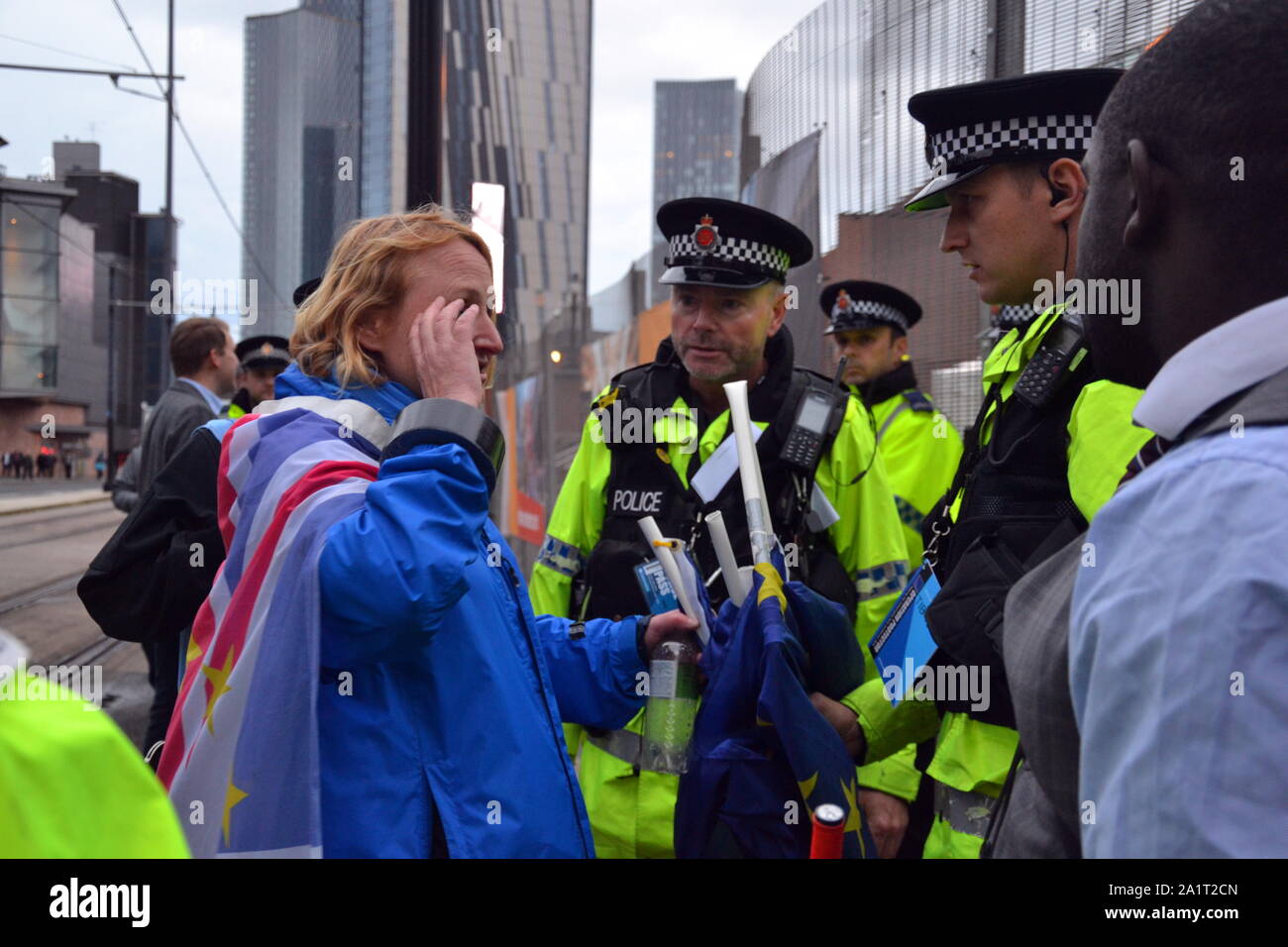 An altercation took place near the main gate of the Conservative Party Conference, 2019, in Manchester, uk, as the conference prepares to start. A member of the Stand of Defiance European Movement, wearing a union jack flag, talks to police after EU flags belonging to the group were allegedly stolen and damaged. The conference prepares to start with a heavy police presence and a few demonstrators as the debate about Brexit reaches a climax. Stock Photo