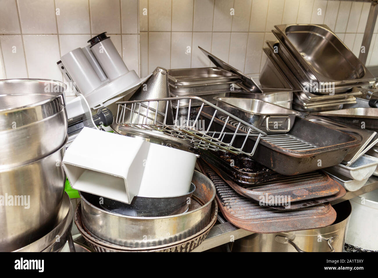 Stack of old baking trays and warming pots in an industrial kitchen Stock Photo
