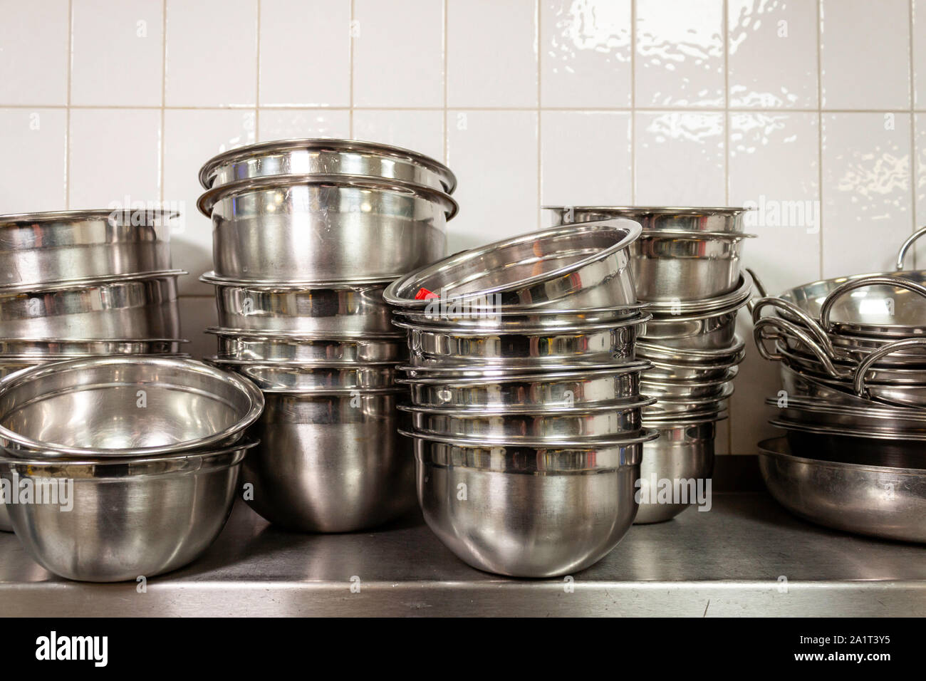 Stacks of stainless steel mixing bowls on a stainless steel shelf in an industrial kitchen Stock Photo