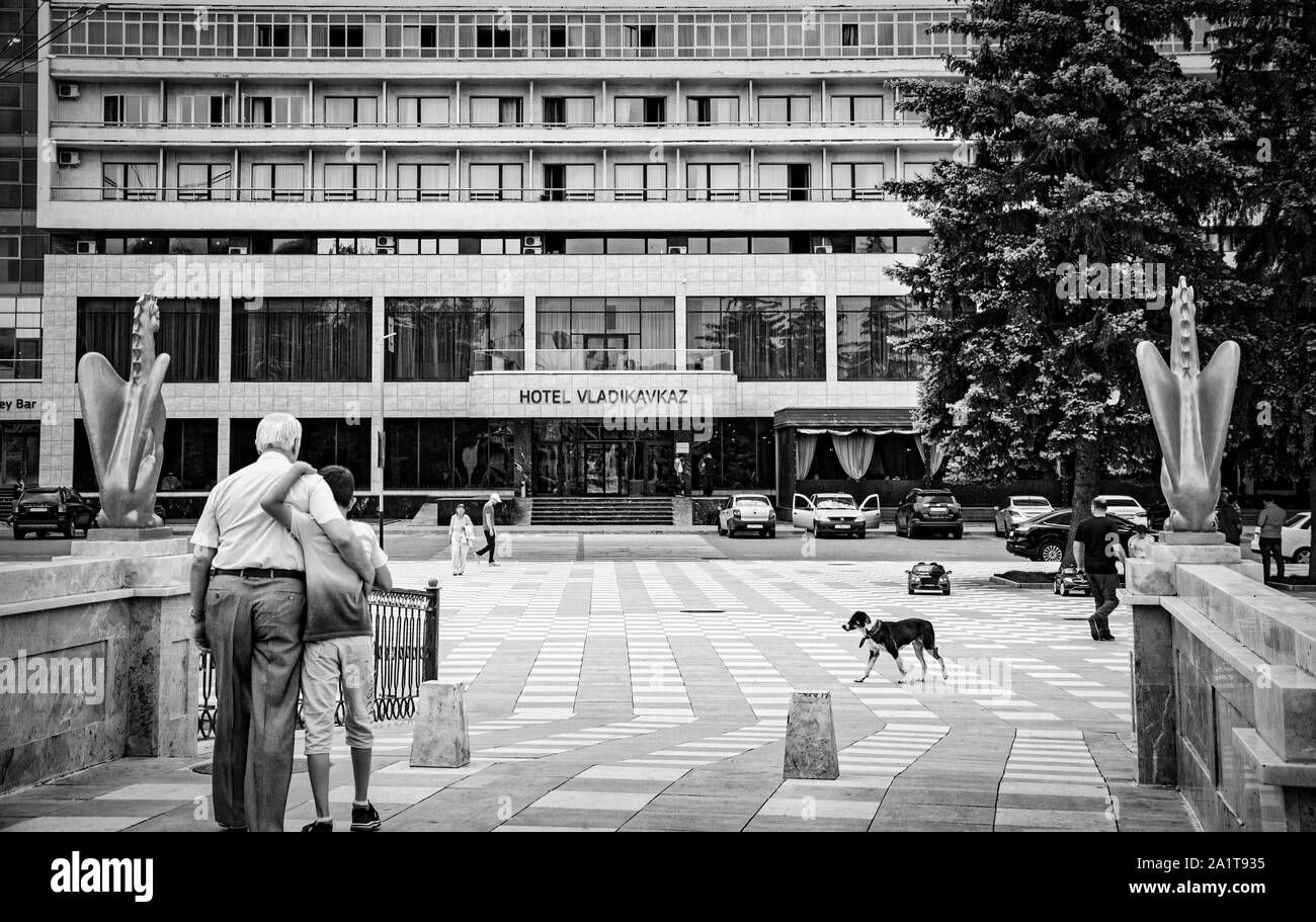Vladikavkaz, Russia - 07 18 2019: hugging granddad and grandson walking in front of hotel Vladikavkaz in the capital of Norhth Ossetia Alania Republic Stock Photo