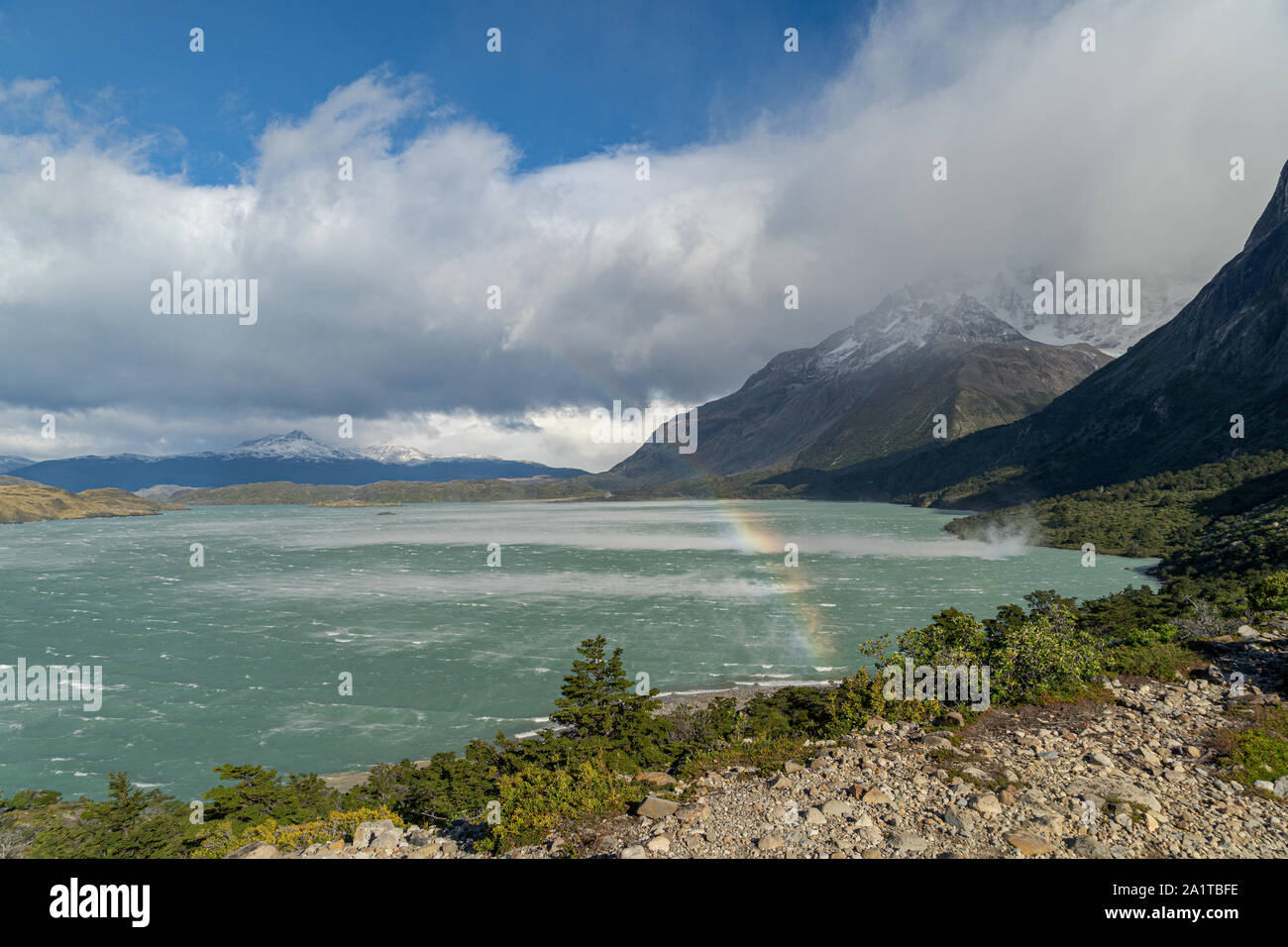 Rainbow over lago nordenskjold, Torres del Paine National Park, Chile. Strong winds pick up lake water and rainbow is created in Torres del Paine Stock Photo