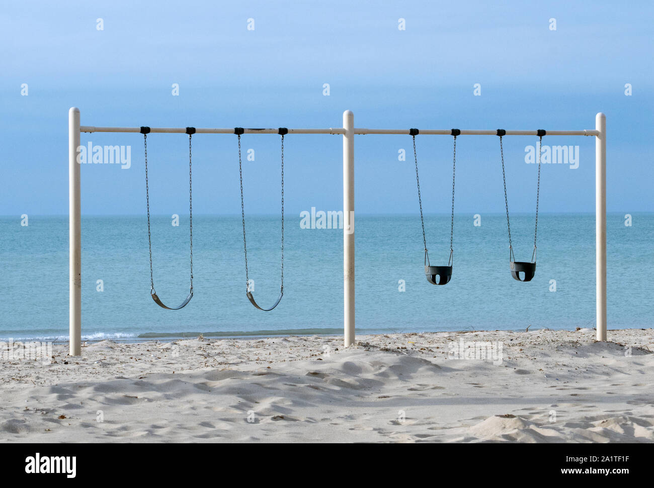 A metal swing set stands on the shores of lake Michigan, ready for happy children to enjoy Stock Photo