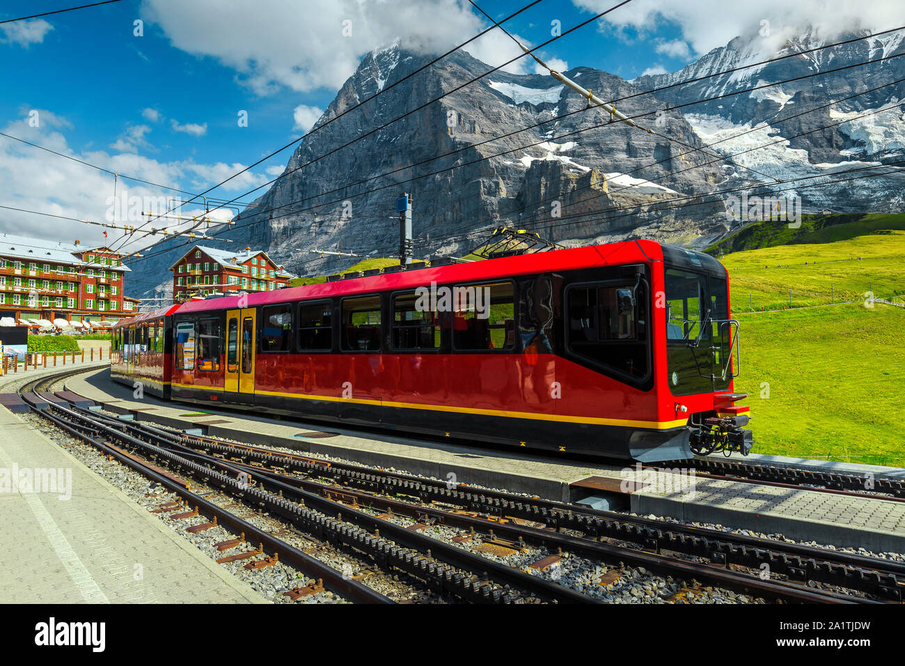 Famous Swiss excursion destination. Spectacular travel and touristic place with high mountains and stunning view. Modern electric red tourist train in Stock Photo